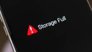A smartphone screen displays a warning message with a red triangle and exclamation mark, reading "Storage Full," alerting users that System Data or Other storage may be taking up significant space.
